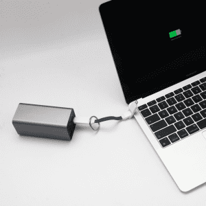 A silver charging cable connected to a laptop, with a visible battery charge indicator on the screen.