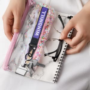 A purple Jacquard keyring with a clip, alongside eyeglasses and a spiral notebook in a clear pouch.