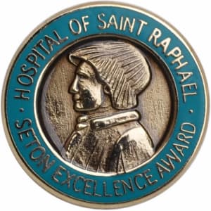 A circular hard enamel pin featuring a profile of a figure with a blue border, embossed with text and a logo.