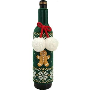 A drink bottle with a green knitted sleeve featuring a gingerbread man, white snowflakes, and pom-pom decorations.