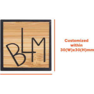 A custom-shaped bamboo lapel pin in a square design featuring a black outline and engraved letter design.