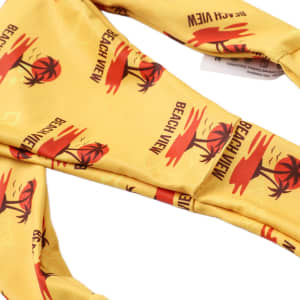 A yellow bikini bottom with a palm tree and sunset pattern, featuring a logo.