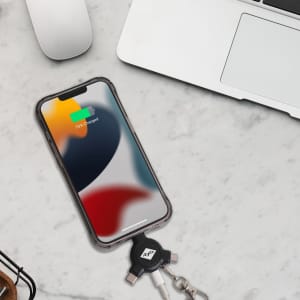 A 3-in-1 ABS data blocker in black with a keyring, placed next to a phone and a laptop on a marble surface.