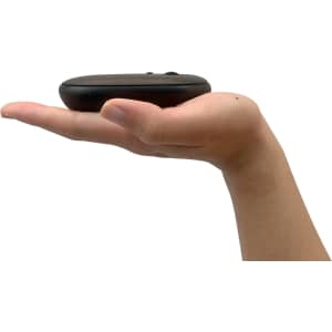 A slim black wireless travel mouse rests in an outstretched hand, showcasing its compact design.
