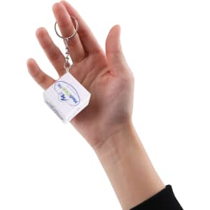 A hand holding a clear 3x3 puzzle cube keyring with a silver chain and ring attachment.