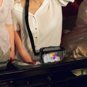 A clear black fanny pack with a strap and branding visible on the front, placed on a surface.
