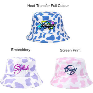 A cow print bucket hat featuring blue and white designs, with branding and embroidered text in various styles.