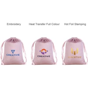 Three pink silk velvet drawstring bags featuring different logos and branding techniques: embroidery, heat transfer, and hot foil stamping.