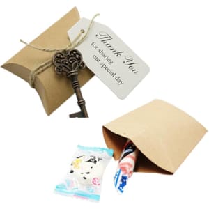 A small brown kraft pillow box with a key and a thank you tag, partially open revealing a candy inside.