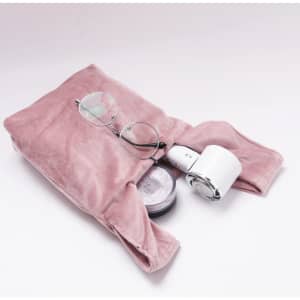 A pink velvet wrist bag containing glasses and a small round container. It has a soft, textured surface.