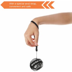 A black and grey wrist ball with a wrist strap, held by a hand, designed for leisure and outdoor activities.