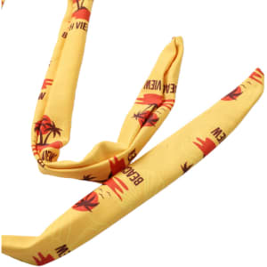 A yellow headband featuring palm trees and sunset designs, with a logo present on the fabric.