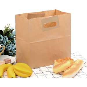 A brown kraft paper bag with handles, surrounded by bananas, pastries, and a decorative plant.