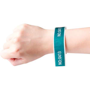A hand wearing a teal disposable Tyvek wristband with a white interior, featuring a simple logo.