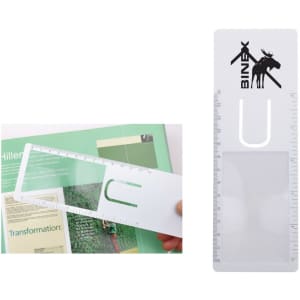 A clear plastic bookmark magnifier with measuring scales and a logo, displayed against a page of text.