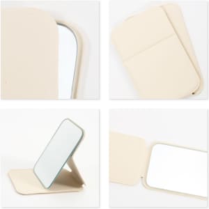 A portable mini mirror in cream, featuring a foldable design with a reflective surface and a protective cover.