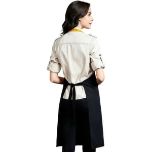 A poly-cotton canvas full bib apron in black with a colourful neck strap, featuring a design logo on the back.