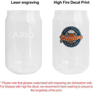 A can-shaped glass cup, featuring a logo on one side and a colourful decal on the other, both in clear glass.