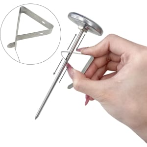 A stainless steel instant read dial thermometer being held, featuring a circular dial and a triangular probe.