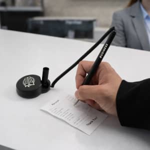A black pen with a coil attached is being used to write on a receipt at a reception desk.