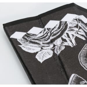 A bamboo fabric hand fan in black with white floral designs and a slim, folded structure. It features branding.