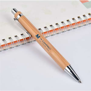 A bamboo pen with a silver clip rests on a lined notebook, featuring a logo on its barrel.