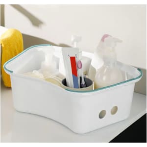 A white storage caddy with various toiletries and a towel, featuring rounded edges and multiple compartments.