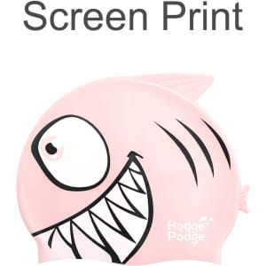 A silicone swim cap in pink, featuring a fish design with prominent eyes and stripes. It has a logo visible.