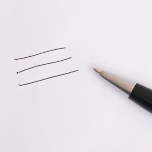 A metal pen with a sleek silver tip next to three evenly drawn black lines on a white paper background.