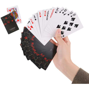A hand holding playing cards, featuring a mix of numbers and suit symbols, with a deck in the background.