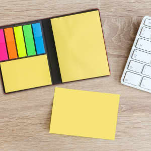 A PU Sticky Notes Memo Holder featuring yellow sticky notes and colourful flags, placed beside a white keyboard on a wooden surface.