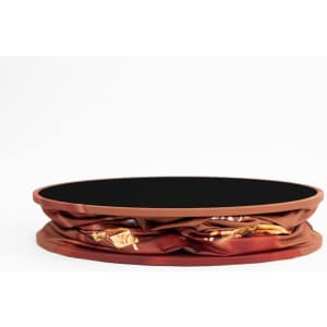 A round display counter with a vibrant brown cover featuring a patterned design. The top has a black surface.