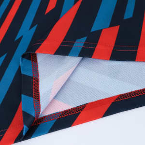 A close-up of a polyester polo shirt featuring a bold red, blue, and black geometric pattern with stitching details.