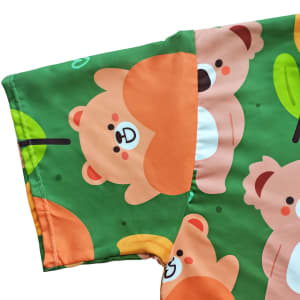A hooded towel poncho featuring a playful bear pattern on a green background with leaves.