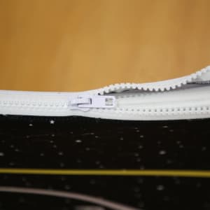 A close-up view of a zippered pouch with a black design featuring stars, highlighting the white zipper.