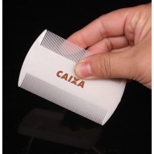 A white pet flea comb held in a hand, featuring fine teeth for removing fleas. It has a branding logo on the side.