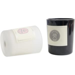 Two glass candles, one white and one black, featuring labels and a logo.