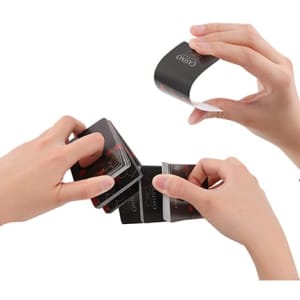 Custom playing cards in black with a logo, being held and fanned out by hands.