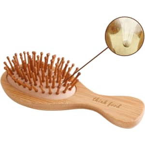A small bamboo hairbrush with wooden bristles and a natural finish. It features a branded logo on the handle.