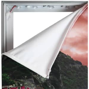A backlit LED light box display with a grey frame and a partially removed fabric graphic.