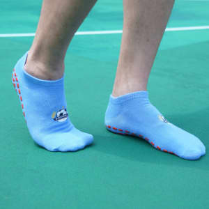 Low cut blue gripper socks featuring a logo and red silicone grips on the sole, displayed on a person's feet.