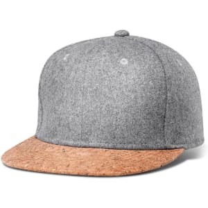 A grey flat cap with a cork brim, featuring a logo on the side.
