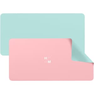 A PU leather desk mat featuring a dual-sided design with mint green and pastel pink colours, including a logo.