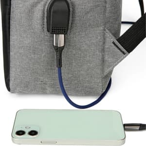 A grey laptop backpack features a USB charging port connected to a phone. The backpack has black accents.
