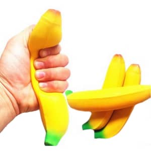 A hand squeezing a yellow banana-shaped stress reliever, alongside two additional bananas. The product has a smooth texture.