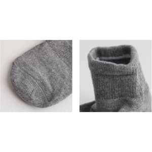 A pair of grey socks with a gripper design, featuring a close-up view of the toe and cuff sections.