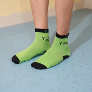 Bright green ankle socks with black accents, featuring a logo and custom pattern design. Ideal for casual wear.