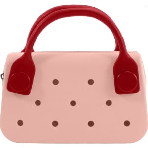 A pink mini handbag with red handles featuring circular holes along the front. It has a simple, stylish design.