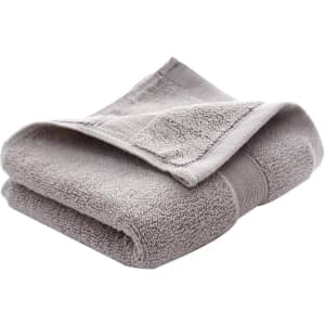 A folded grey embroidered cotton hand towel with a textured finish. It has a band around the centre and a logo.