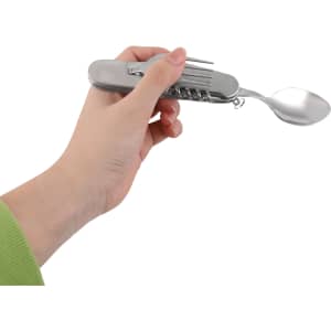 A stainless steel camping cutlery tool held in a hand, featuring multiple utensils and a logo.